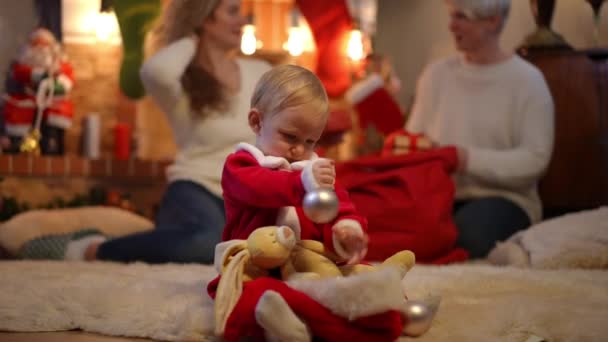 Mooie Baby Meisje Spelen Met Decoraties Kerstavond Als Vrouwen Inpakken — Stockvideo