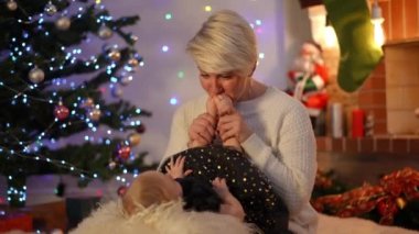 Minik bebek ayaklarını öpen, suratını buruşturan, evde çocukla oynayan pozitif bir kadın. Yeni yıl arifesinde yeğenimle Noel tatili yaparken gülümseyen beyaz halamın portresi.