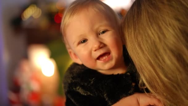 特写可爱的白人女婴看着摄像机笑着拥抱难以辨认的女人 圣诞前夜 可爱可爱的幼儿在家中慢动作的画像 — 图库视频影像