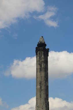 Bulutlu arkaplanı olan Tugu Muda anıtının bir parçası.