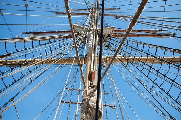 Ropes and the mast to control the sails, details of the device of the yacht, sailing ship equipment against the blue sky, horizontal view