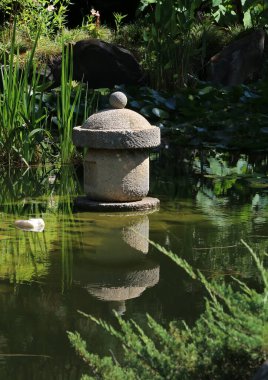 Stone pedestal in a pond, an element of a Japanese garden in a public park