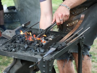 Demirci ocağı, demircinin elleri demirci aletleriyle çalışıyor, kömür ve yangın, yakın plan.