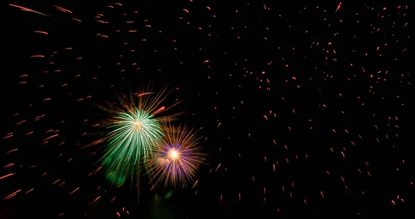 Two bright multicolored flashes of fireworks flying through sparks against black sky. Copy space — Stock Photo, Image