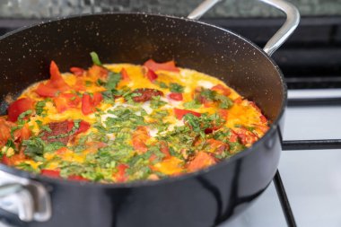 Sebzeli omlet ve beyaz sobada siyah tavada otlar.. 