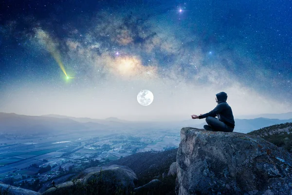 在山上的人晚上与银河和月亮一起在户外冥想或祈祷 — 图库照片