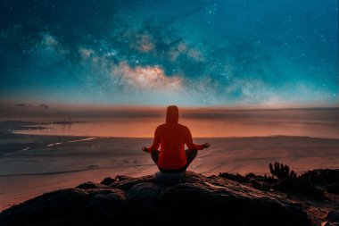 Bilinmeyen kişi dağın tepesinde oturuyor. Okyanusun üzerinde meditasyon yapıyor. Samanyolu 'nun arka planında, arka planda.