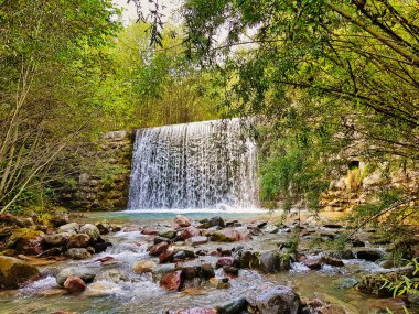 Avusturya 'nın Vorarlberg eyaleti Meng, Walgau nehrinde şelale. Taştan yapılmış eski baraj, nehirdeki ıslak kayalar ve yeşil yapraklar.