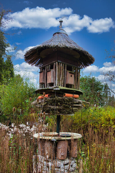 Big insect hotel and nesting boxes on a pole, built of all kinds of wood and reeds