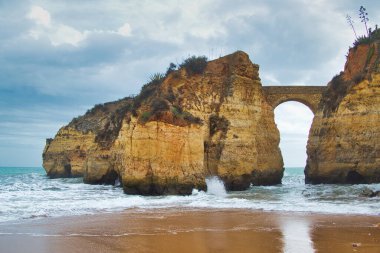 Anakarayı küçük, kayalık bir adaya bağlayan antik taş köprü, Lagos, Portekiz, Algarve. Fantezi bir filmden fırlamış gibi..