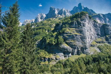 Mountain scenery with high cliffs, forests and towering peaks in the Cirque du Fer--Cheval in the French Alps, part of the national park Sixt-Passy in the department of Haute-Savoie
