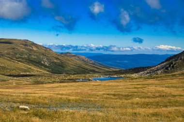 Kosciuszco Ulusal Parkı, Yeni Güney Galler, Avustralya 'da küçük gölü, bulutları ve otlağı olan dağ manzarası