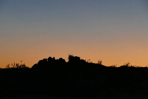 Silhouette Von Felsen Und Pflanzen Vor Orangefarbenem Abendhimmel — Stockfoto