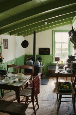 Leens, Netherlands, 4-24-2022. Traditional kitchen in a 19th-century Dutch farmworker's cottage, with a set table, wood stove, kettles and a sloped wooden ceiling. Verhildersum, province of Groningen, Netherlands