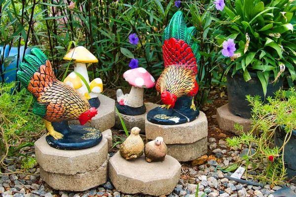 Garden ornaments of colorful chickens, chicks and  toadstools in a garden in Thailand