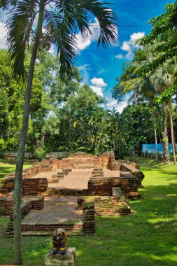 Wat Chang Kam 'ın tuğla tapınağı yıkıntısı, Tayland, Chiang Mai' deki Wiang Kum Kam arkeolojik sahasında palmiye ağaçları ve diğer tropikal bitki örtüsü.
