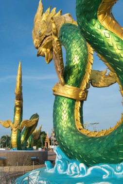 Large statues of green and gold nagas (mythical serpents) on the Mekong riverside promenade in Nong Khai, Thailand