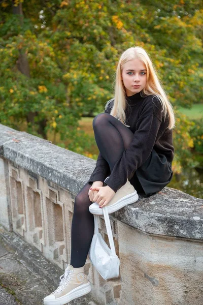 Nehir ve ağaçlarla sonbahar parkında poz veren kız