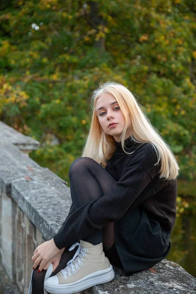 Nehir ve ağaçlarla sonbahar parkında poz veren kız