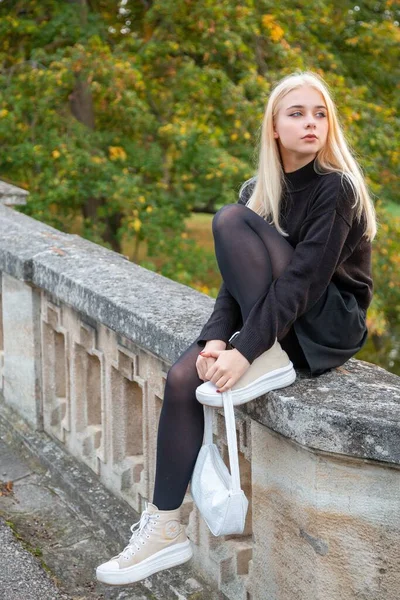 Nehir ve ağaçlarla sonbahar parkında poz veren kız