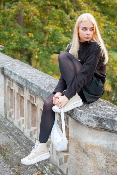 Nehir ve ağaçlarla sonbahar parkında poz veren kız