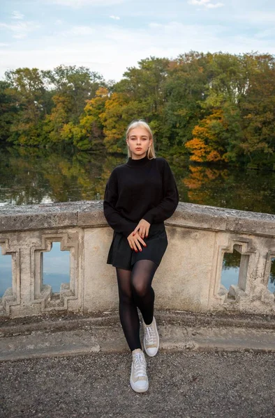 Nehir ve ağaçlarla sonbahar parkında poz veren kız