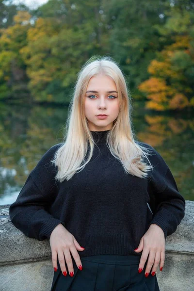 Nehir ve ağaçlarla sonbahar parkında poz veren kız