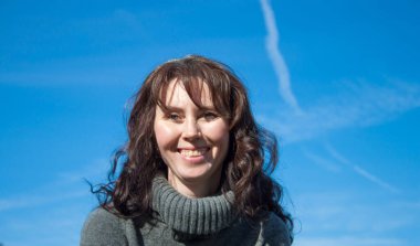 Mavi gökyüzüne karşı gülen bir kadın.