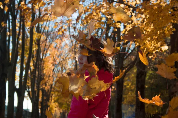 Une fille sur le fond d'une forêt d'automne. Feuilles d'automne volantes. — Photo