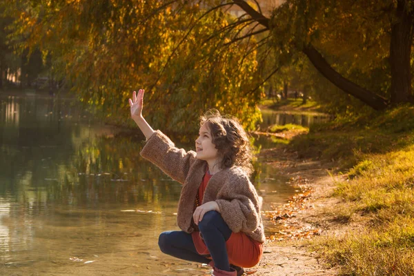 Une fille joue avec l'eau dans un parc d'automne. — Photo