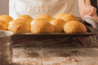 Bir kadın fırın tepsisini çöreklerle tutar.