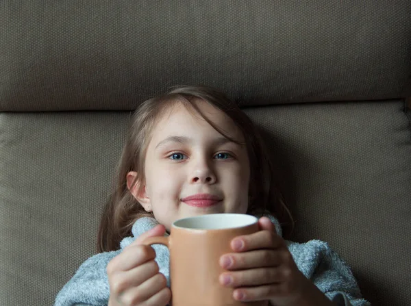 Uma menina sorrindo segura uma xícara de cacau. — Fotografia de Stock