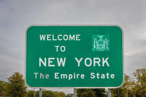 A Welcome to New York state line highway sign marking the border with the Commonwealth of Pennsylvania.