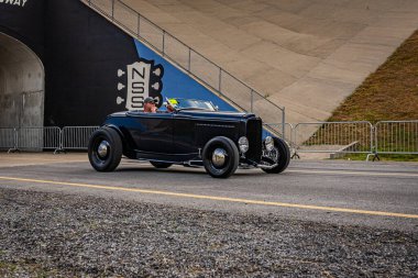 Lebanon, TN - May 14, 2022: Wide angle front corner view of a 1932 Ford Highboy Roadster driving on a road leaving a local car show.