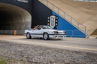 Lebanon, TN - May 14, 2022: Wide angle front corner view of a 1985 Ford Mustang GT convertible driving on a road leaving a local car show.