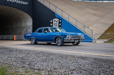 Lebanon, TN - May 14, 2022: Wide angle front corner view of a 1965 Chevrolet Impala 4 Door Hardtop Sedan driving on a road leaving a local car show.