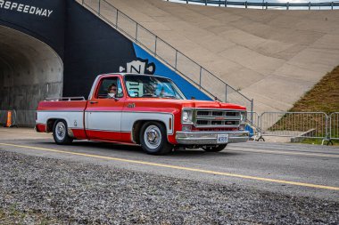 Lebanon, TN - May 14, 2022: Wide angle front corner view of a 1976 GMC Sierra Classic 1500 Pickup Truck driving on a road leaving a local car show.