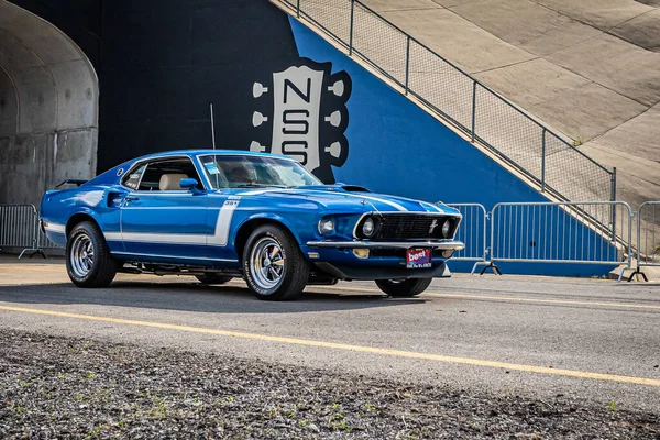 Lebanon, TN - May 14, 2022: Wide angle front corner view of a customized 1969 Ford Mustang Mach 1 Fastback driving on a road leaving a local car show.