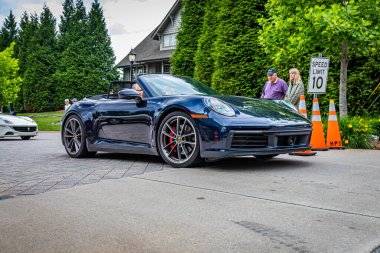 Highlands, NC - June 10, 2022: Low perspective front corner view of a 2020 Porsche 911 Carrera 4S Cabriolet leaving  a local car show.