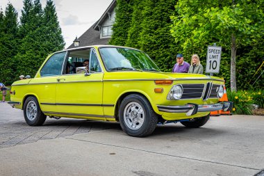 Highlands, NC - June 10, 2022: Low perspective front corner view of a 1973 BMW 2002 Tii Hardtop coupe leaving  a local car show.