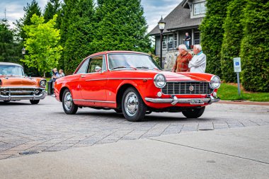 Highlands, NC - June 10, 2022: Low perspective front corner view of a 1966 Fiat 1500 Spider Hardtop Coupe leaving a local car show.