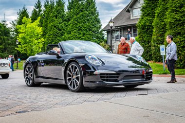 Highlands, NC - June 10, 2022: Low perspective front corner view of a 2014 Porsche 911 Carrera 4 Cabriolet leaving a local car show.