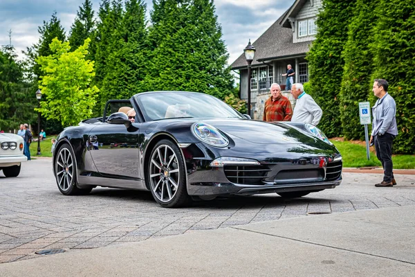 Highlands, NC - June 10, 2022: Low perspective front corner view of a 2014 Porsche 911 Carrera 4 Cabriolet leaving a local car show.