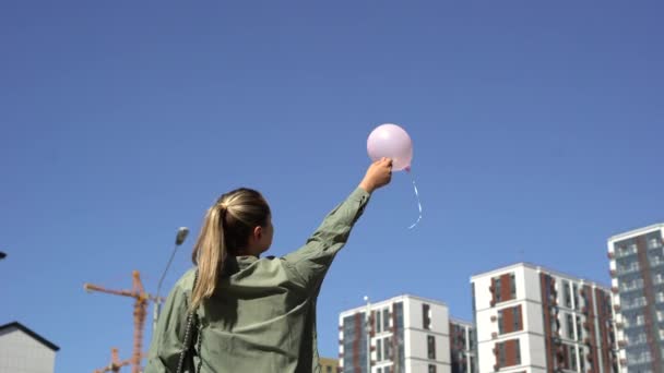 Жінка з рожевою кулею, піднімає повітряну кулю вгору і відлітає — стокове відео