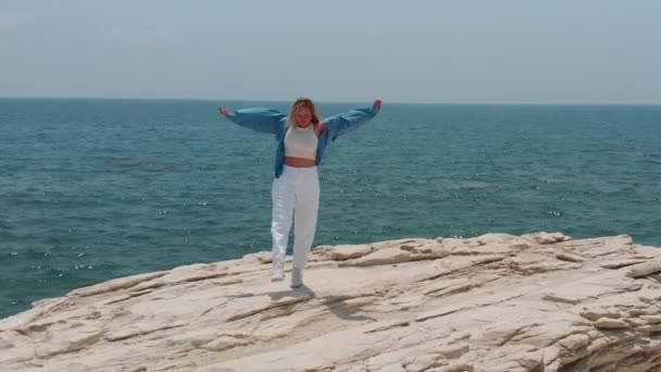 Feliz joven caminar en una costa rocosa cerca del océano, día de verano soleado en Chipre — Vídeos de Stock