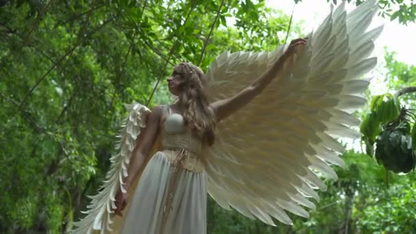 Костюм ангела-юной женщины открывается белое крыло крупным планом глядя в камеру — стоковое видео
