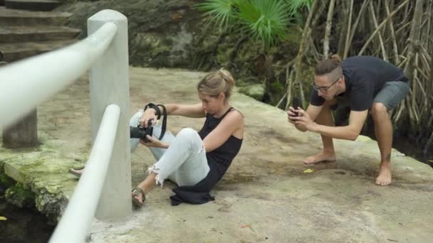 Fotógrafo y asistente haciendo fotos Usando cámara profesional y teléfono — Vídeo de stock