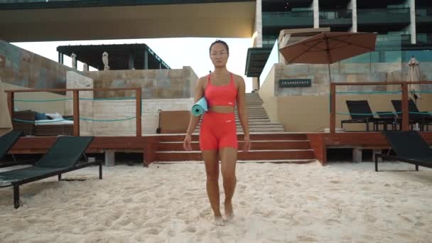Jovem menina andar na câmera em sportswear depois de uma sessão de ioga perto da praia e do mar — Vídeo de Stock