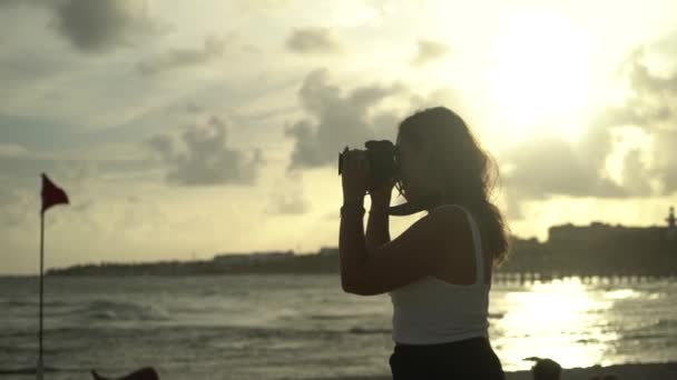 Bela fotógrafa do sexo feminino tirar fotos do pôr do sol. Movimento lento — Vídeo de Stock