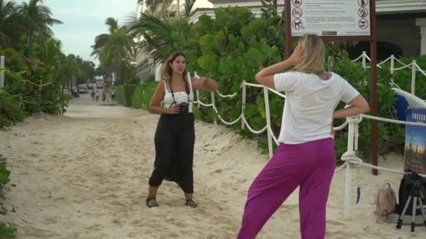 Meksika 2021. Plajda bir fotoğrafçıya poz veren pembe pantolonlu genç bir kadın. Telifsiz Stok Video